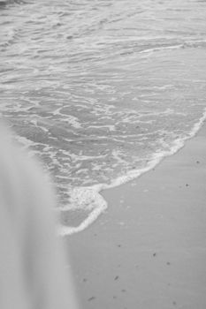 Tranquil black and white photo of gentle ocean waves on a sandy beach in Porto Seguro, Brazil.