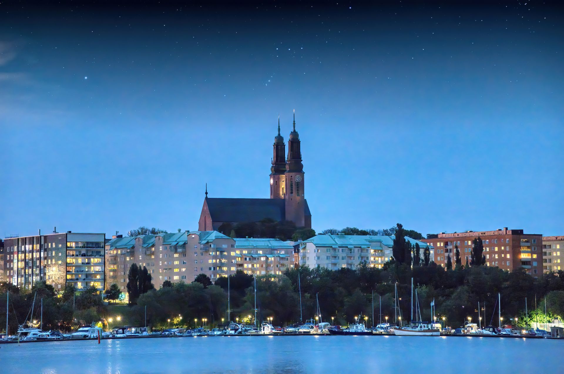 Scenic night view of Södermalm, Stockholm with illuminated skyline and church under starry sky.
