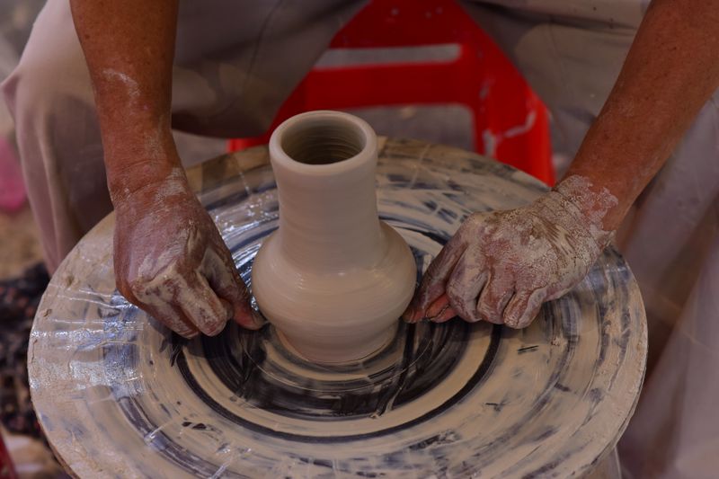 Close-up of hands crafting pottery vase on spinning wheel, showcasing artisanal skills.