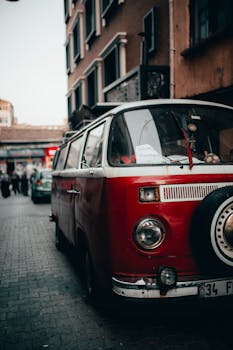 A classic red minibus parked on a quiet urban street, reflecting nostalgic charm and retro vibes.