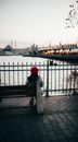 Unrecognizable woman contemplating city river under bridge in evening