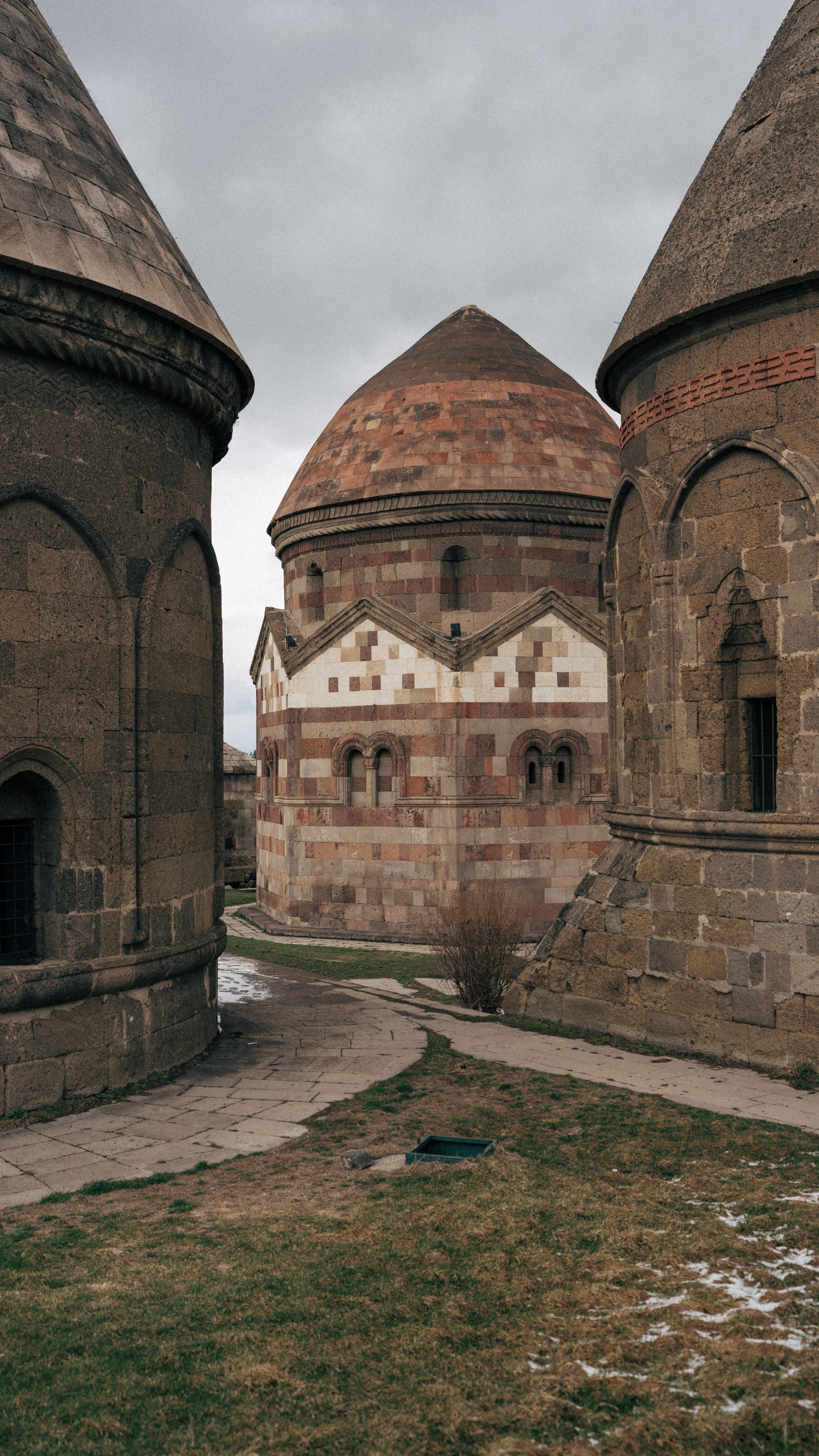 Ancient stone mausoleums with intricate designs under a cloudy sky, showcasing historic architecture.