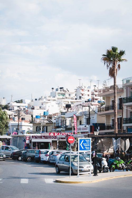 Free Modern cars in parking lot on asphalt road with signs near palm tree and houses on hillside under cloudy sky in summer in town Stock Photo