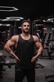 Athletic man showcasing strength in the gym, wearing a black tank top.
