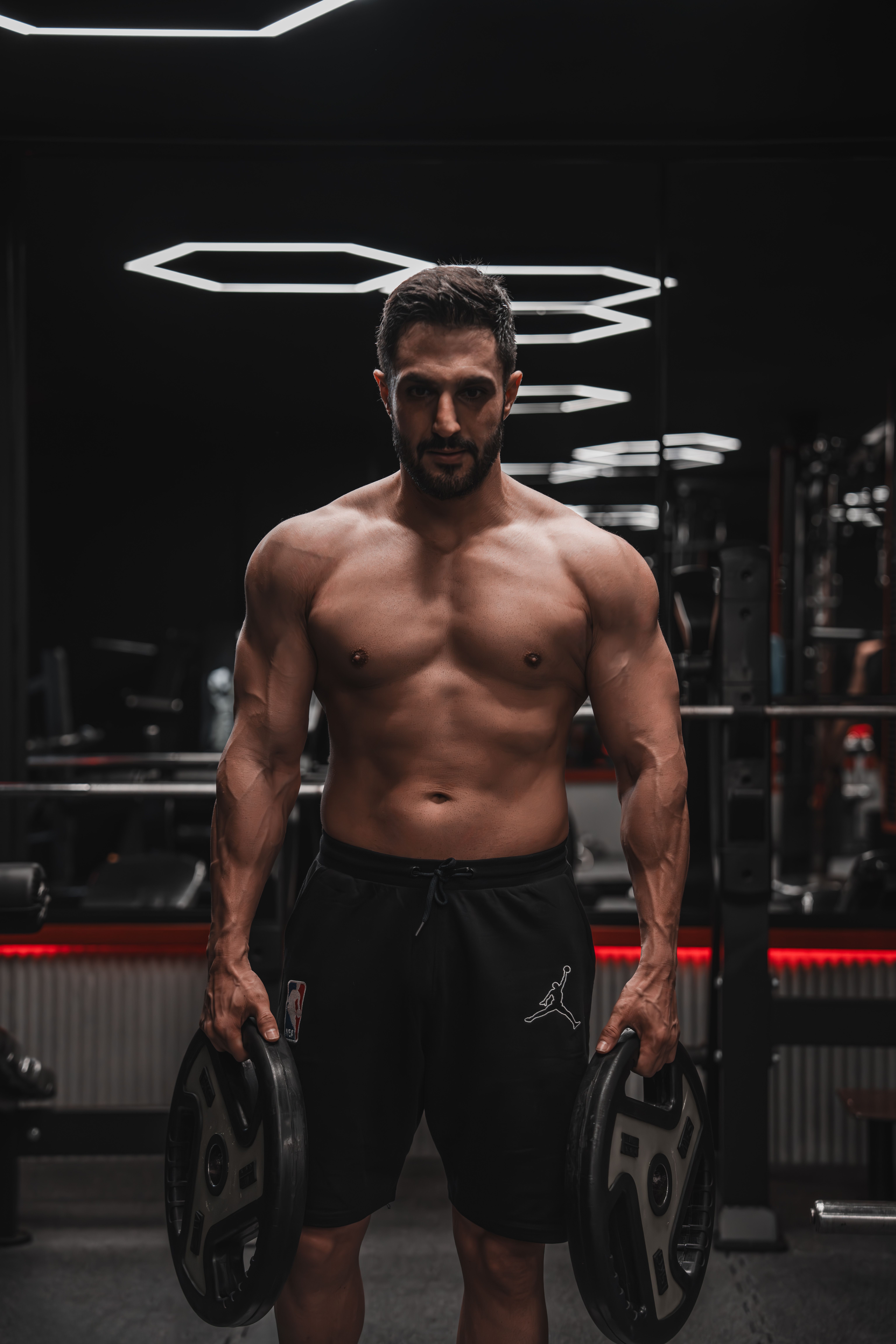 Muscular man lifting weights in a modern gym, showcasing strength and fitness.