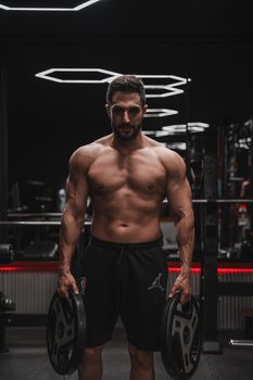 Muscular man lifting weights in a modern gym, showcasing strength and fitness.