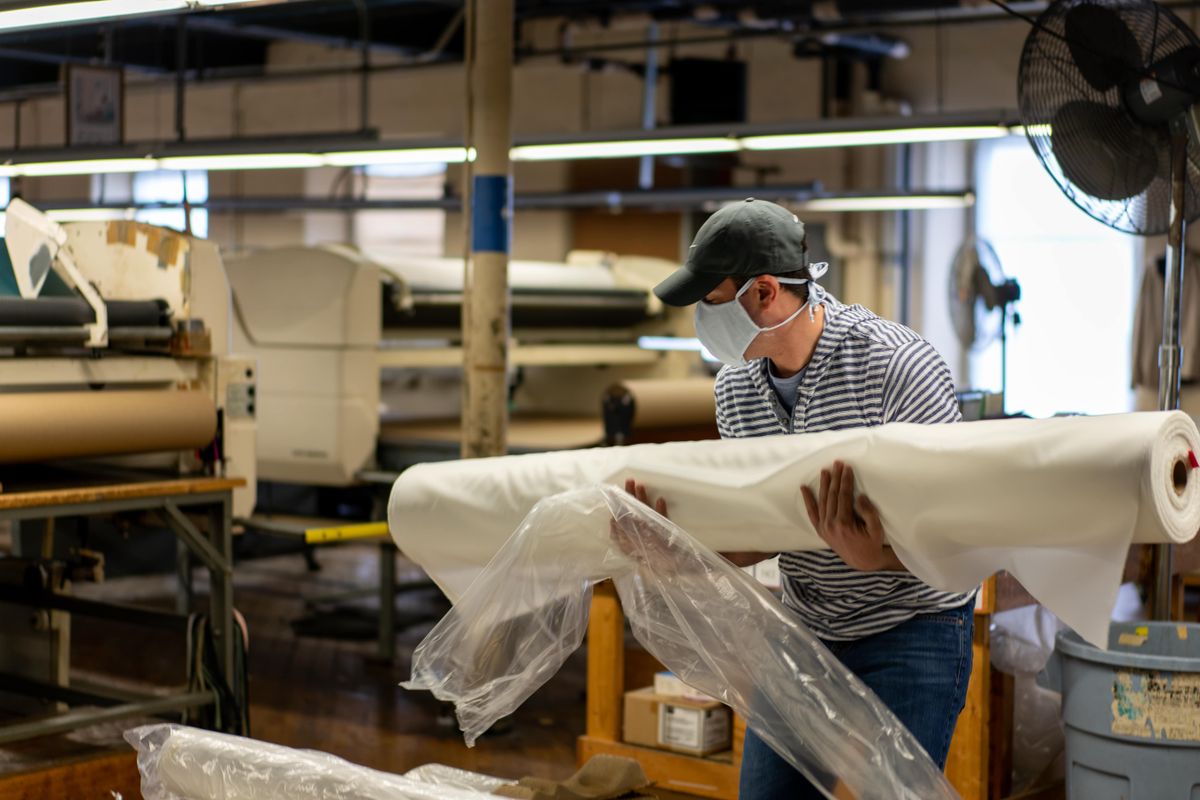 Factory worker handling flexible roll materials during production