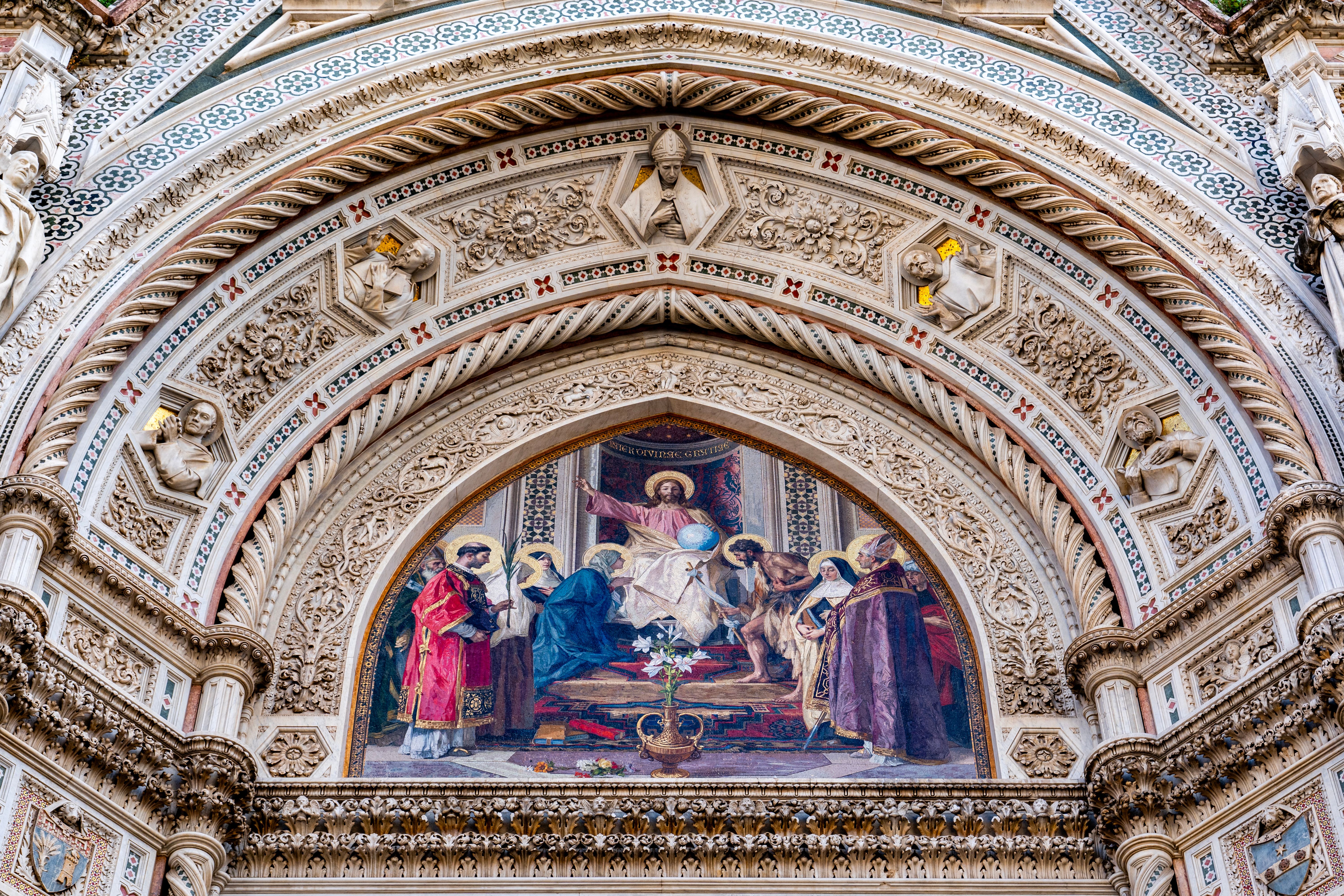 Close-up of Florence Cathedral's ornate facade showcasing religious frescoes and sculptures in Tuscany, Italy.