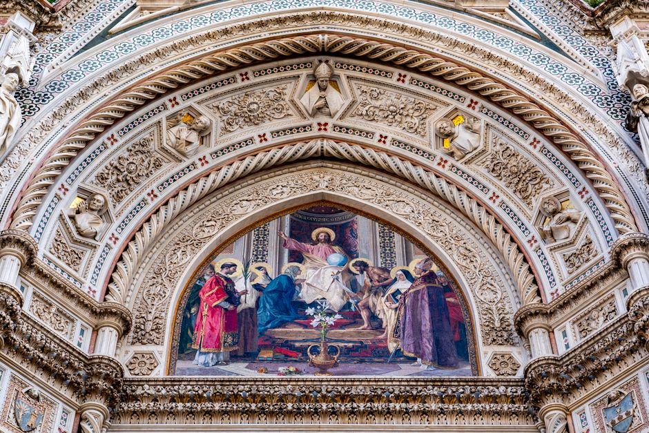 Close-up of Florence Cathedral's ornate facade showcasing religious frescoes and sculptures in Tuscany, Italy.