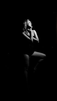 Striking black and white portrait of a woman posing gracefully against dark background.