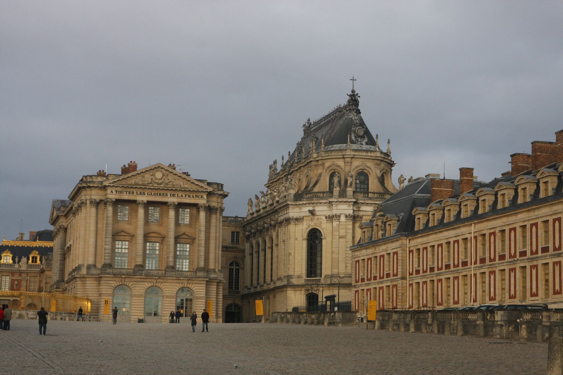 Historic Versailles Palace showcasing classic French architecture under a cloudy sky.