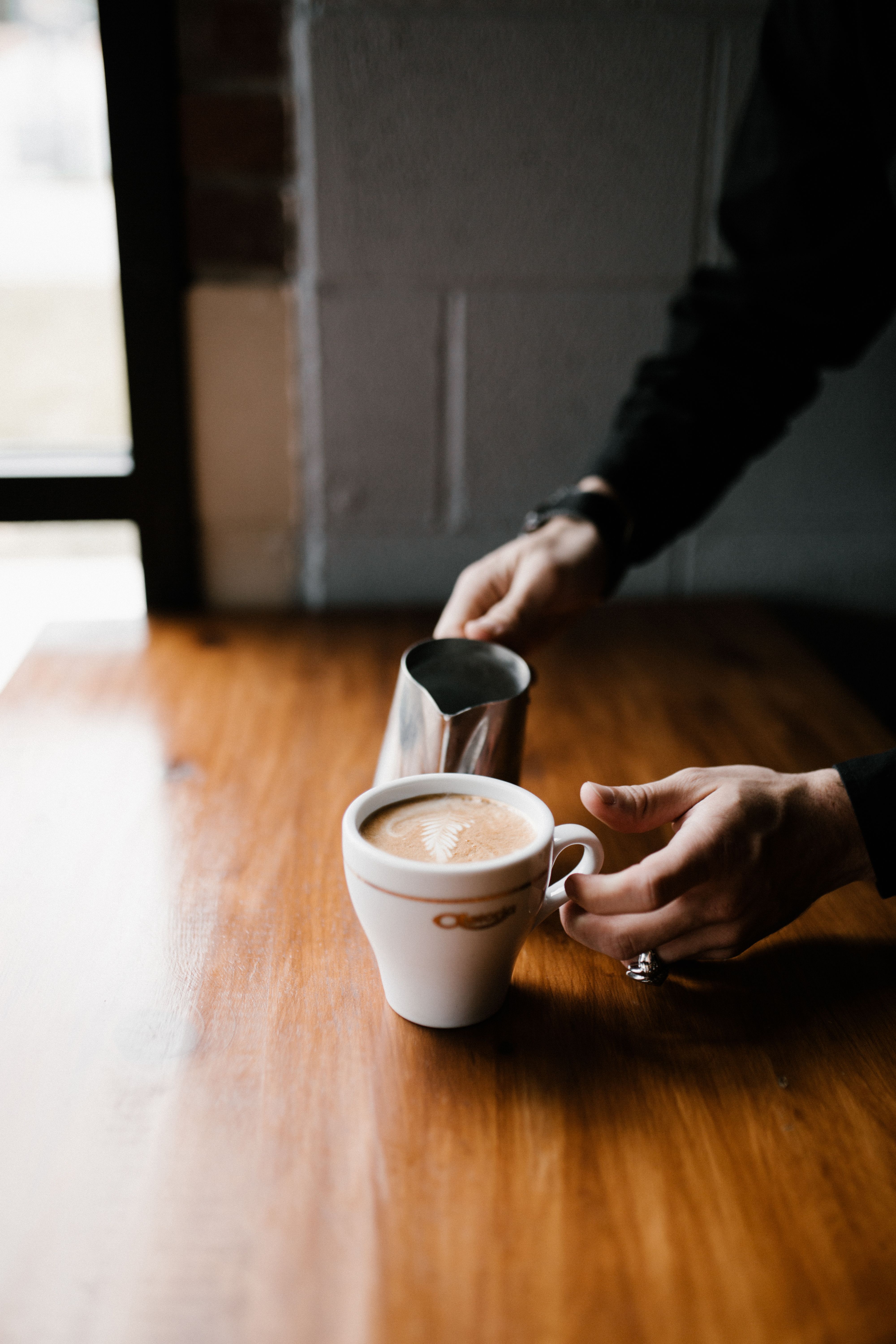 Barista skillfully adds milk to coffee in a cozy Greensboro café setting.
