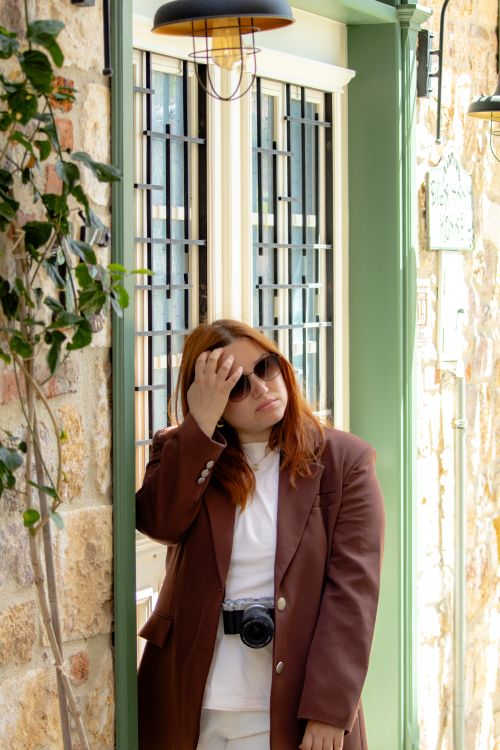 Free Fashionable woman in sunglasses poses in Ayvalık, Türkiye. Cozy, rustic setting with plants. Stock Photo