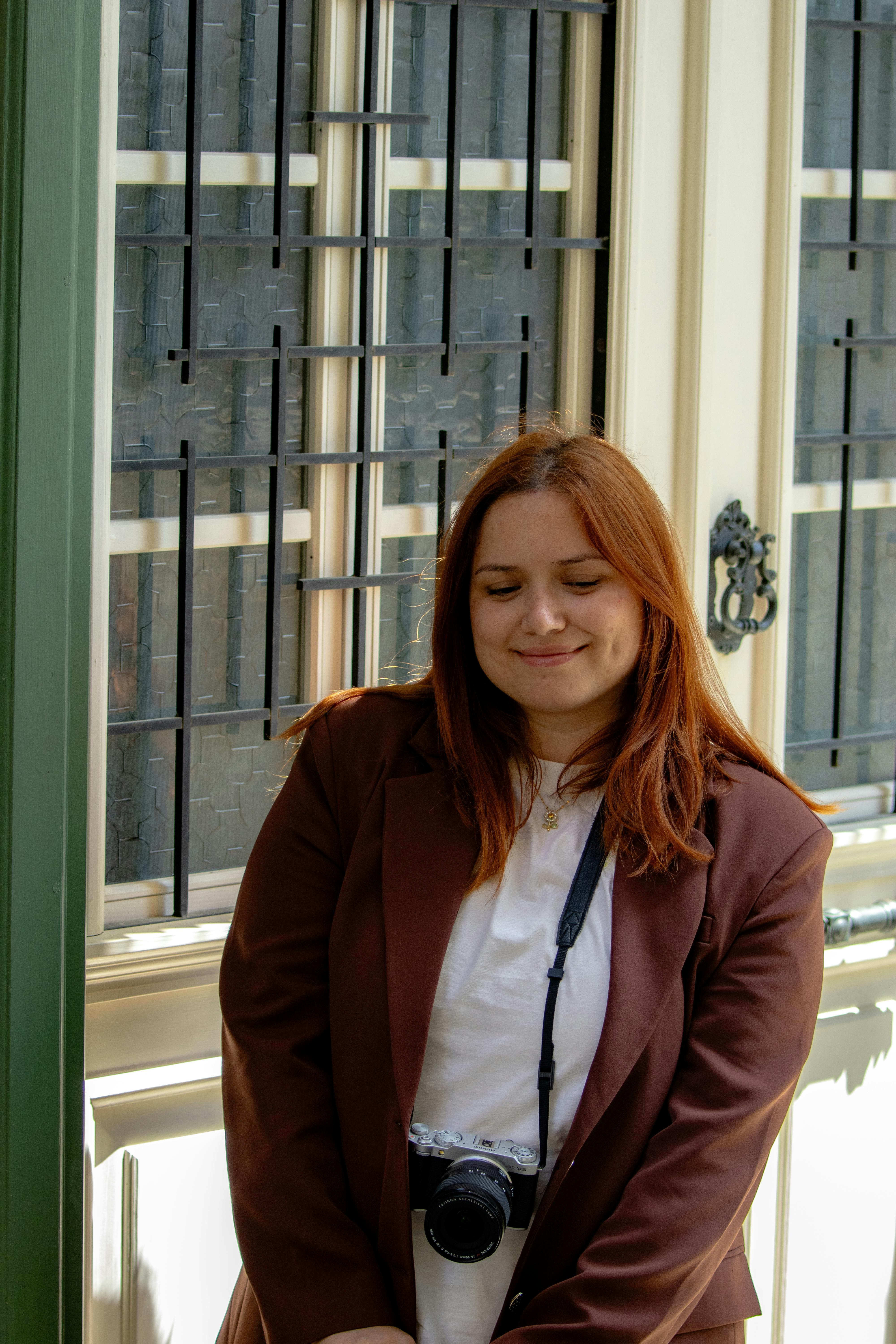 Woman in a brown jacket with a camera, enjoying a moment of calm.