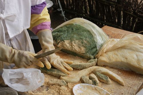 Free A person preparing Korean rice cakes with gloved hands and traditional tools outside. Stock Photo