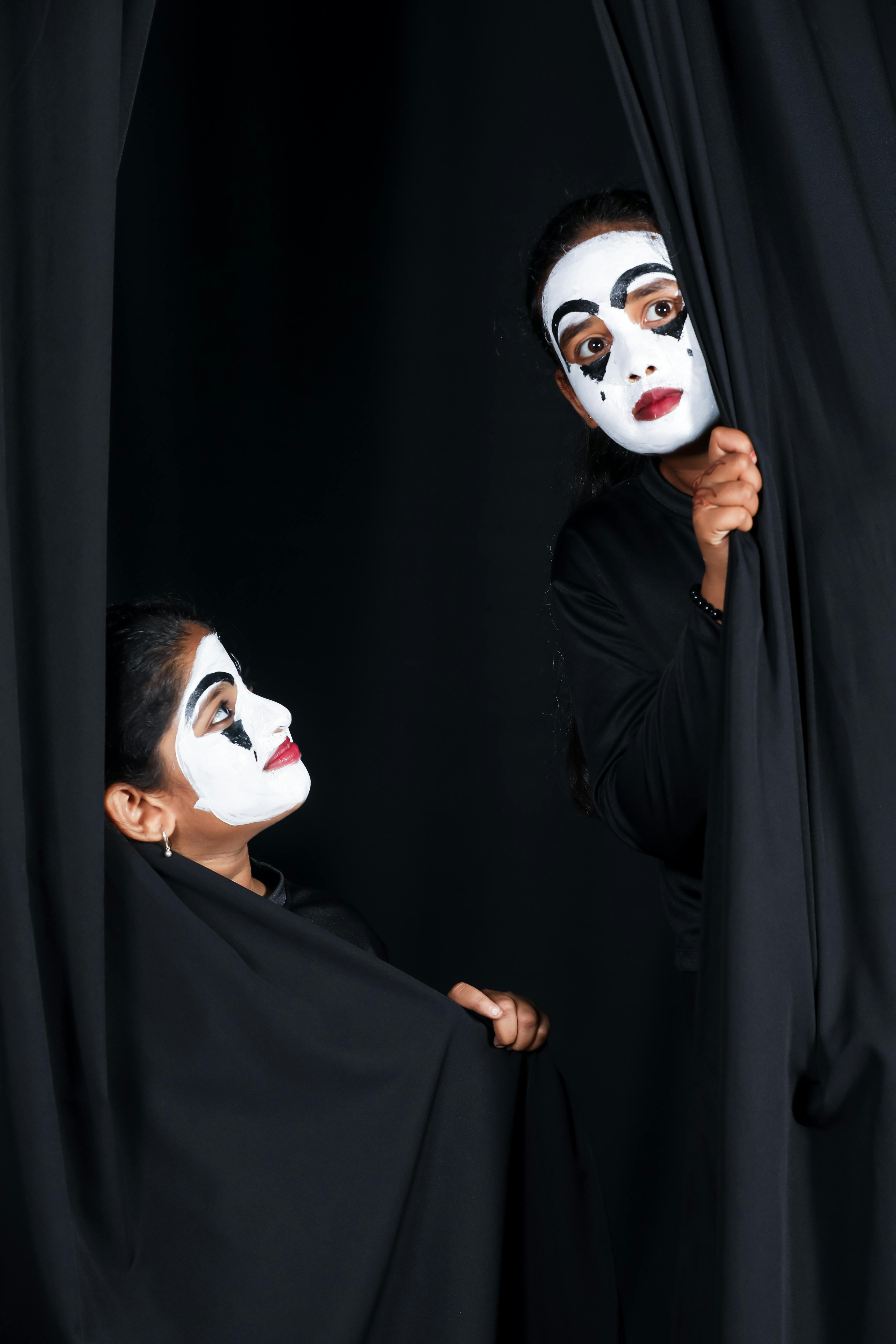 Free Two mime artists in dramatic black and white makeup performing on stage with curtain backdrop. Stock Photo