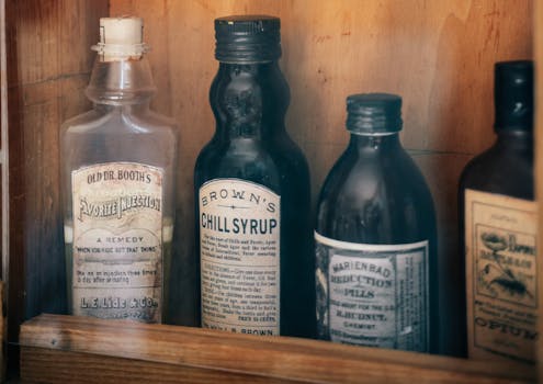 A collection of antique medicine bottles with vintage labels in a wooden cabinet, Valletta, Malta.