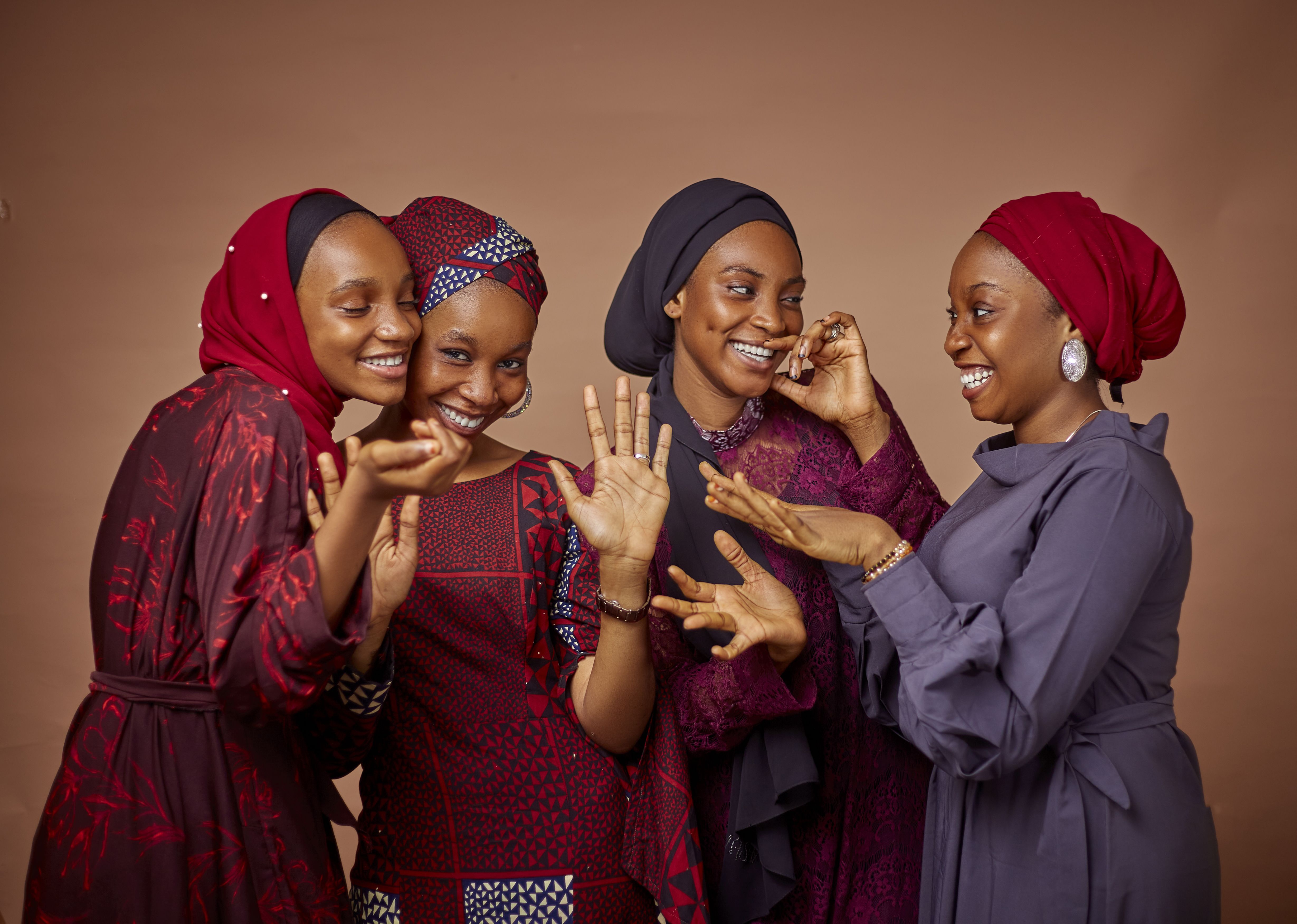 Four women in vibrant traditional clothing share joyful moments together.