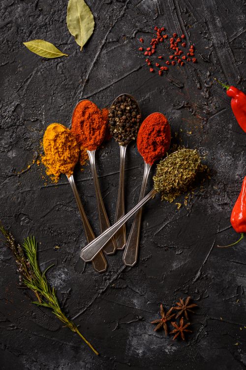 Free A top-down view of assorted spices on spoons against a dark textured surface, showcasing vibrant colors. Stock Photo