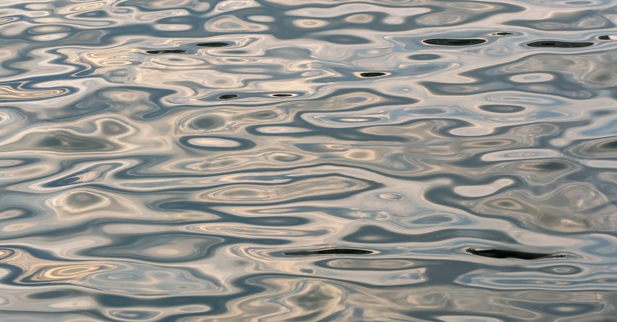 Tranquil Water Surface with Reflective Ripples · Free Stock Photo