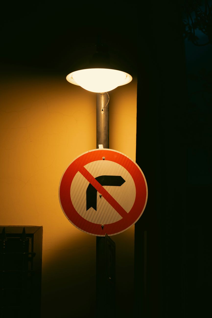 Placa de proibido virar à direita iluminada sob um poste de luz à noite em uma esquina de rua urbana.