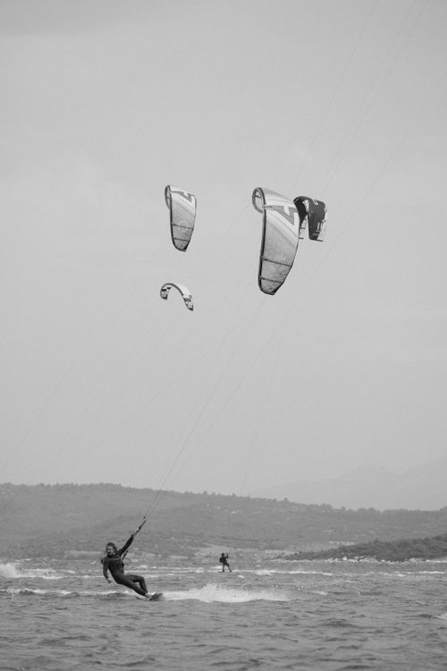 Free Exciting kite surfing scene capturing three kite surfers against a distant mountain backdrop. Stock Photo