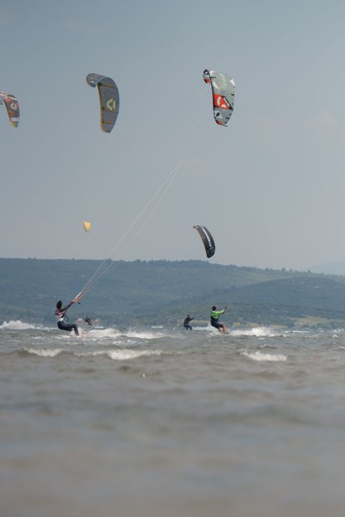 Free A group of kitesurfers enjoying a sunny day on the water with scenic hills in the background. Stock Photo