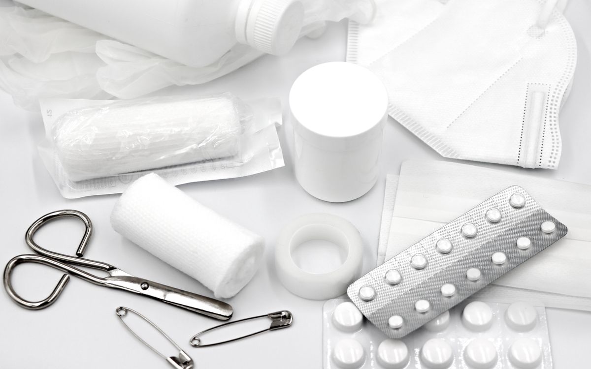 A flat lay of essential first aid supplies and medical equipment on a white background.