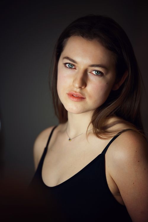 Free Close-up portrait of a young woman with dark background, soft lighting. Stock Photo
