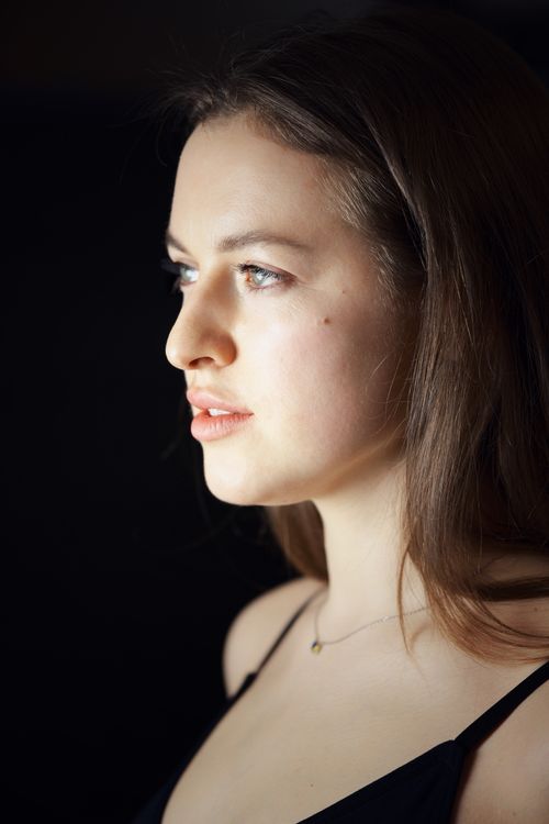 Free Side profile of a young woman with dramatic lighting casting shadows. Stock Photo