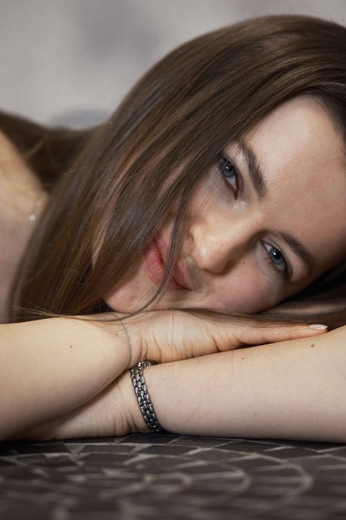 Free Intimate portrait of a woman lying down with a relaxed smile and long hair. Stock Photo