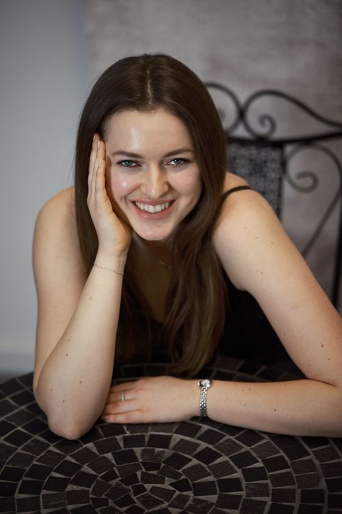 Free Smiling woman leaning on a mosaic table indoors, exuding joy and warmth. Stock Photo