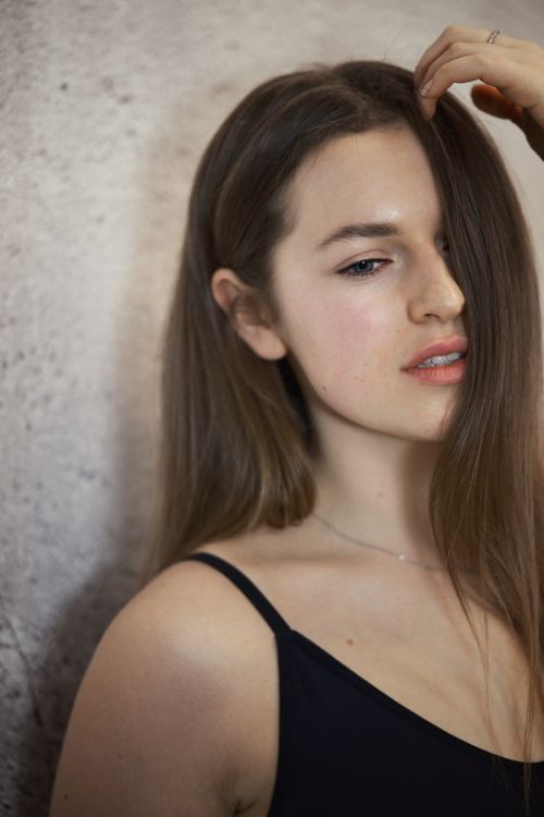 Free Close-up portrait of a young woman with long hair against a neutral backdrop. Stock Photo