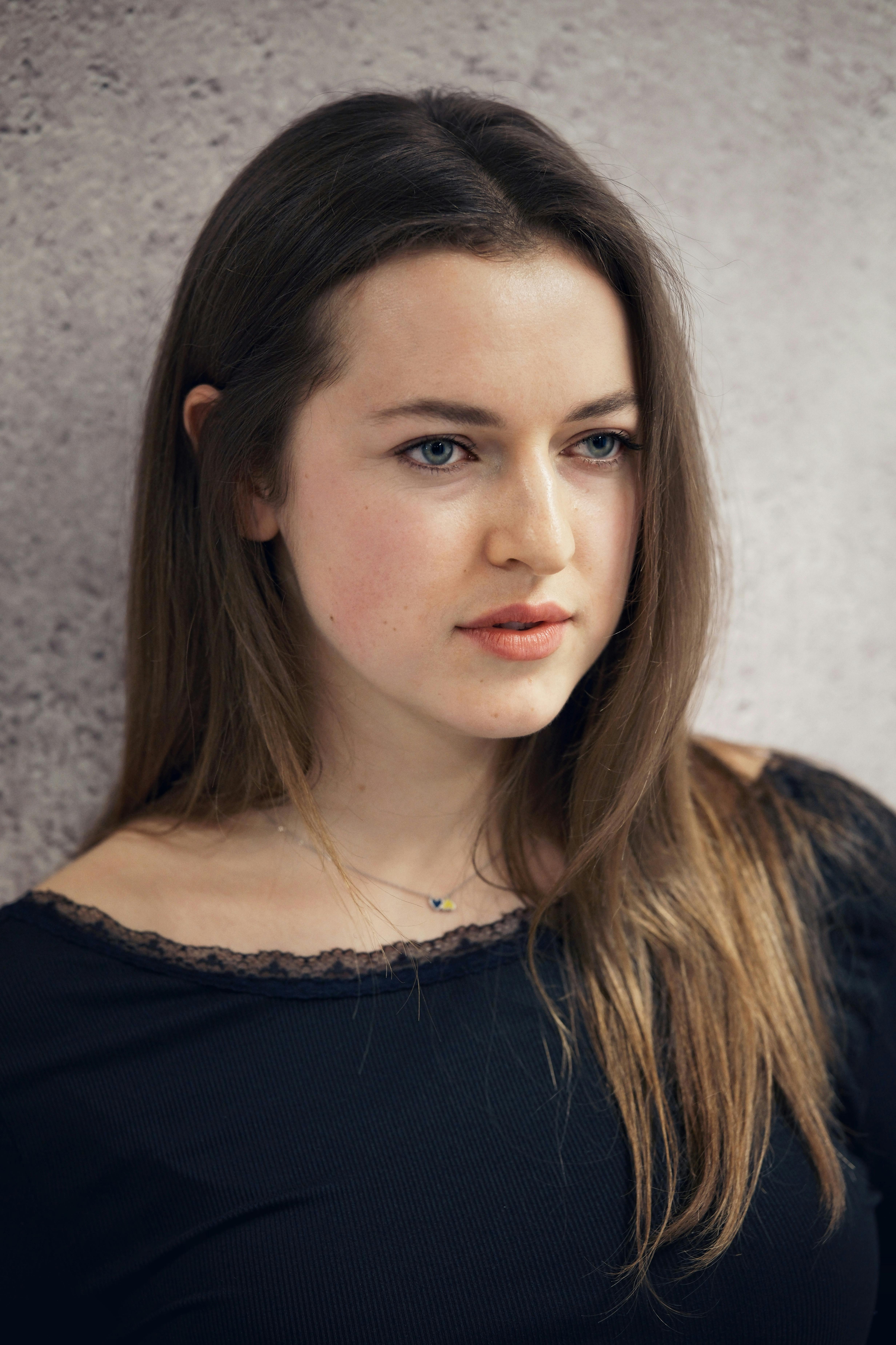 Close-up portrait of a young woman with long brown hair and casual attire.