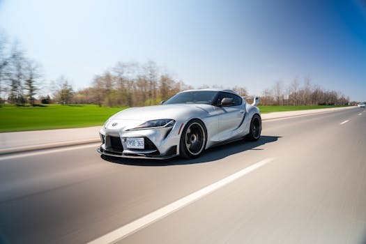 Dynamic shot of a silver sports car speeding on a clear highway under a blue sky.