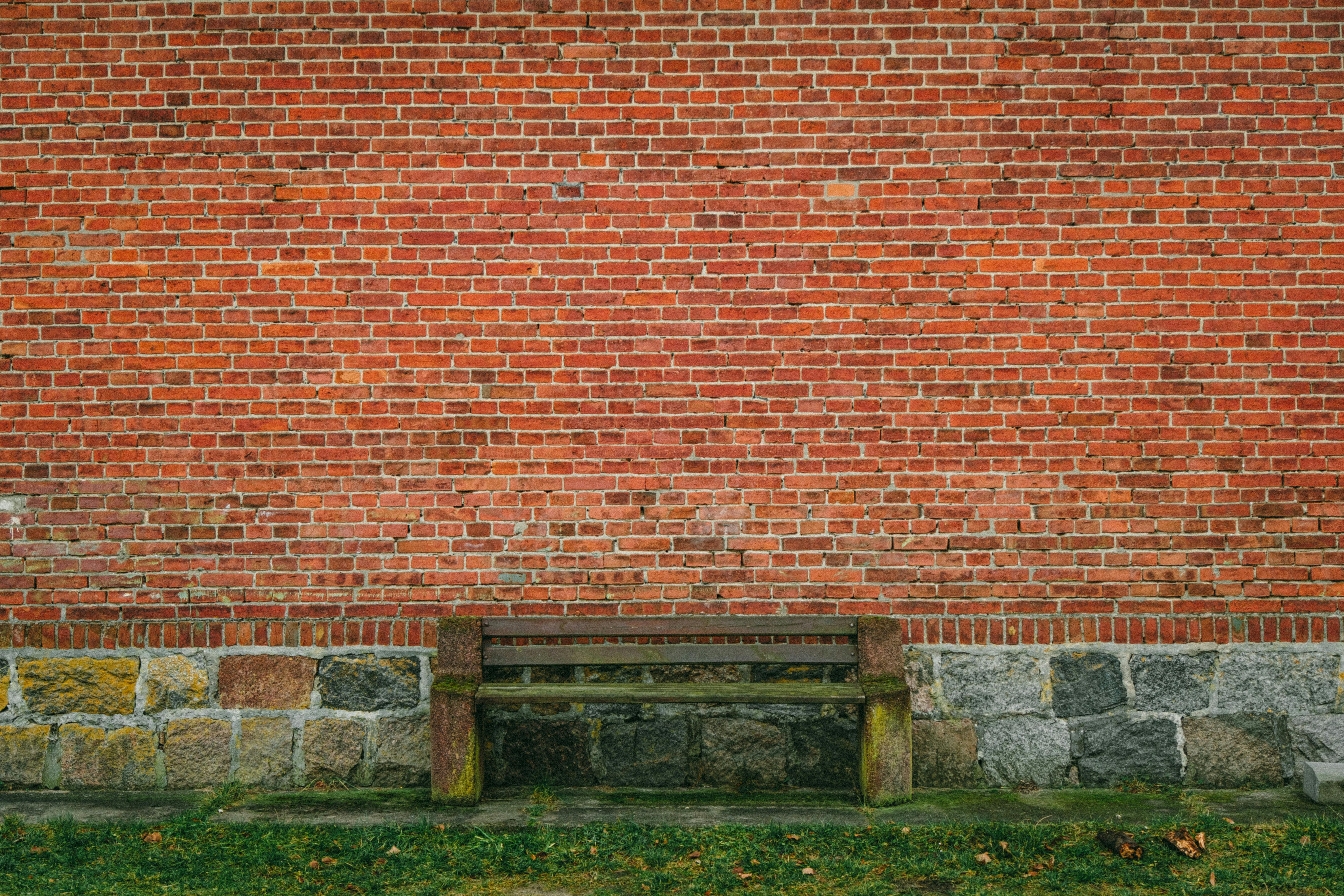 Gratis En ensom bænk op mod en rustik murstensvæg i Polen indfanger ensomhed og enkelhed. Lagerfoto