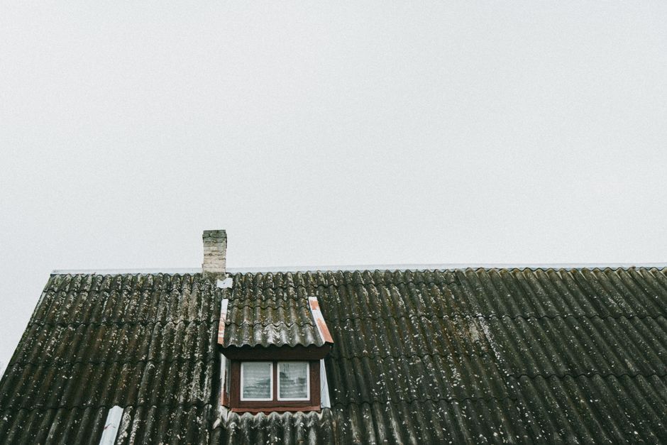 A vintage roof with a small window and chimney in Poland, showcasing old architectural charm.