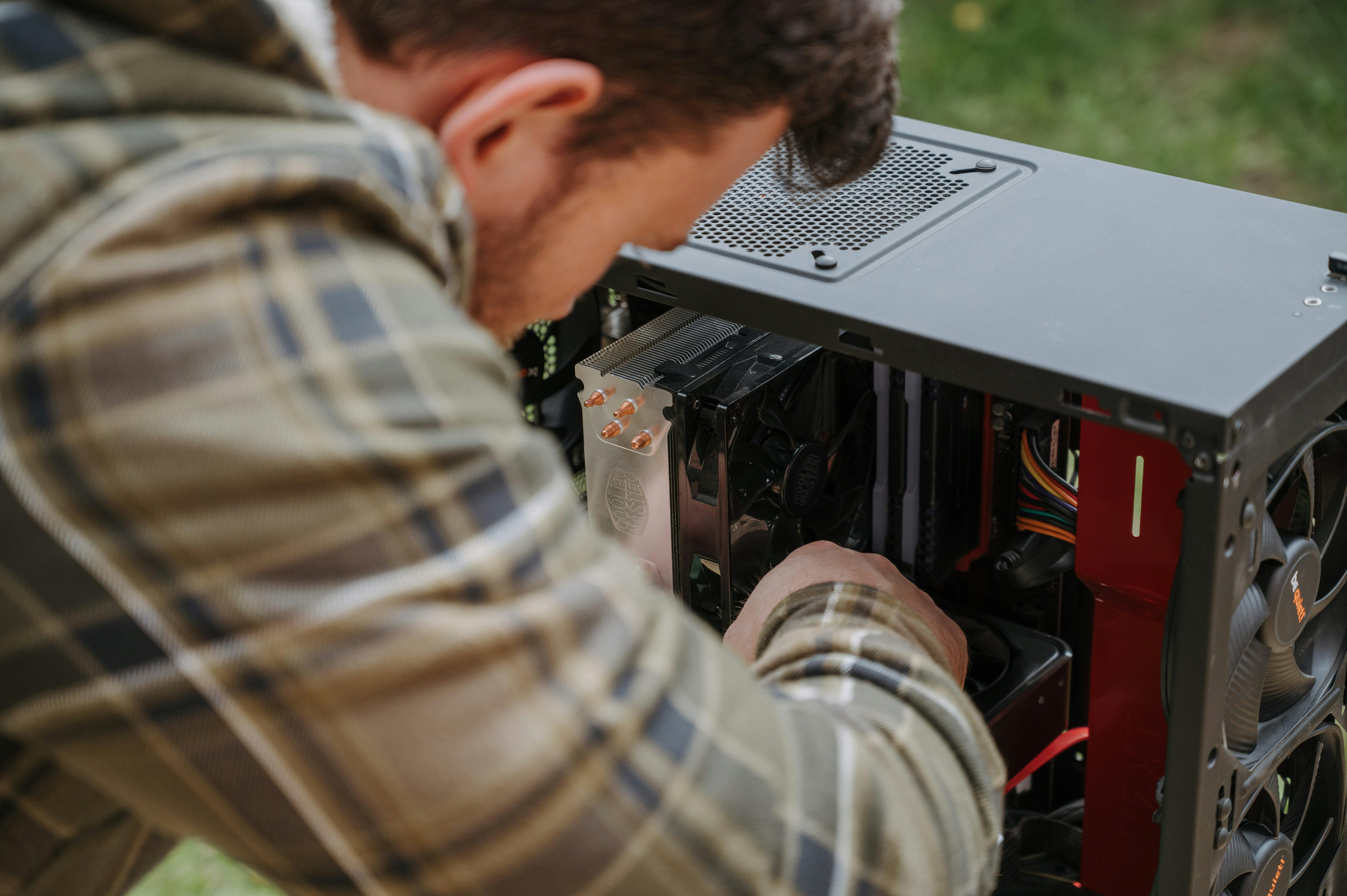 Man performing DIY computer maintenance outdoors · Free Stock Photo
