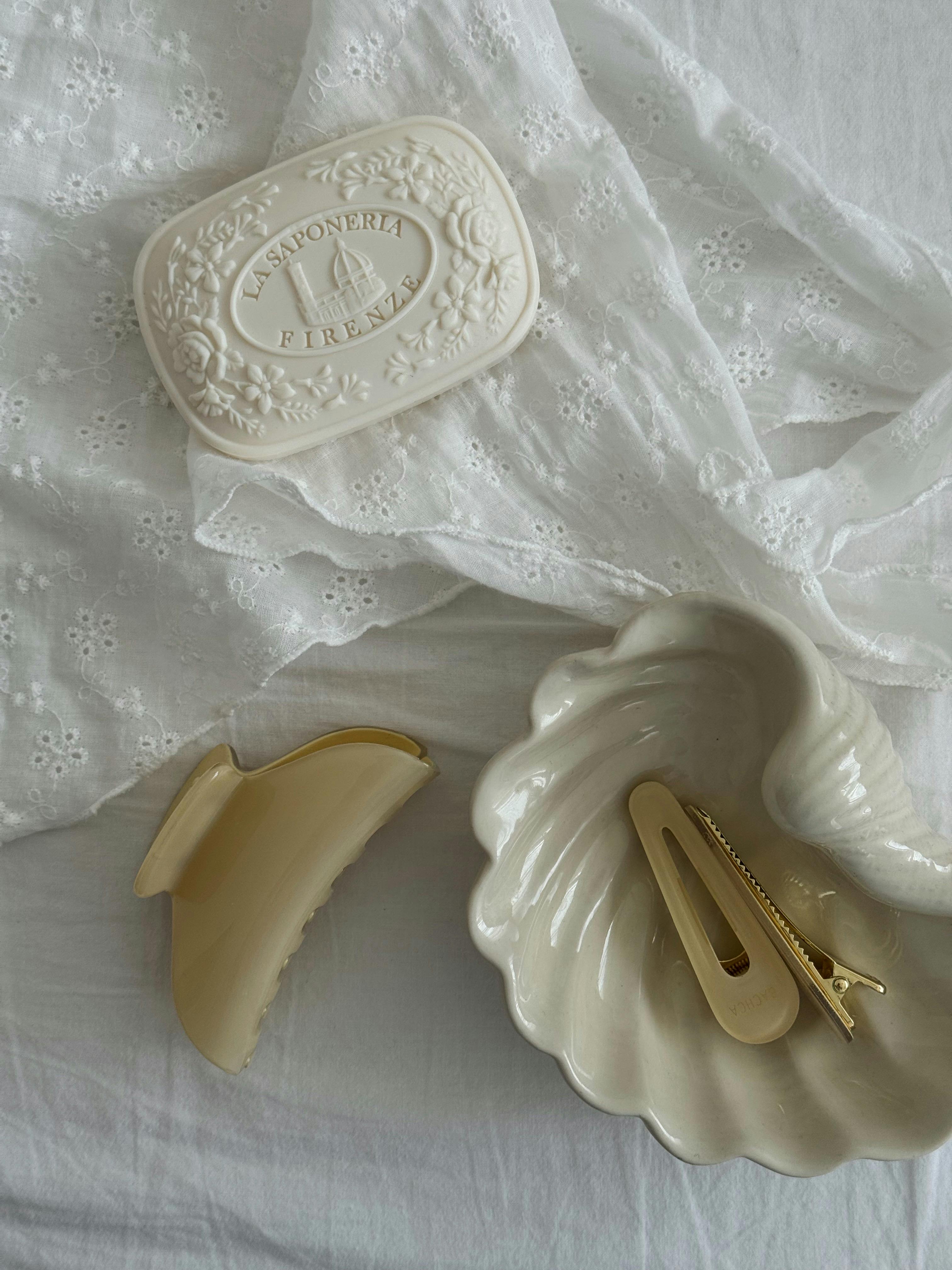 Aesthetic flat lay of soap, hair clips and delicate textiles in soft, neutral tones.