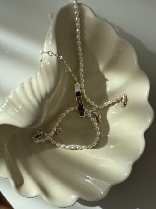 Free Close-up of pearl necklace and bracelet in a shell-shaped bowl, with sunlight creating a serene mood. Stock Photo