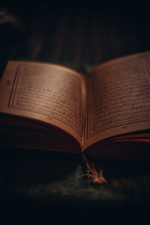 Free Dimly lit open book with Arabic text evokes mystery and contemplation. Stock Photo