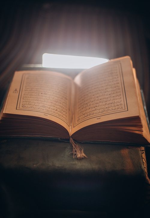 Free Open book with Arabic text under a warm light, creating a serene and contemplative mood. Stock Photo