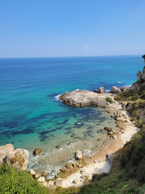 Free A breathtaking view of a turquoise sea, rocky shore, and blue sky. Stock Photo