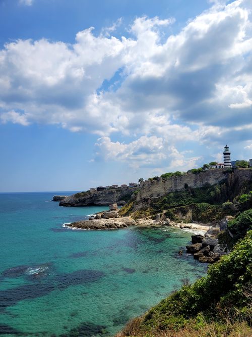 Free Breathtaking coastal view featuring a lighthouse on a cliff with turquoise waters below. Stock Photo