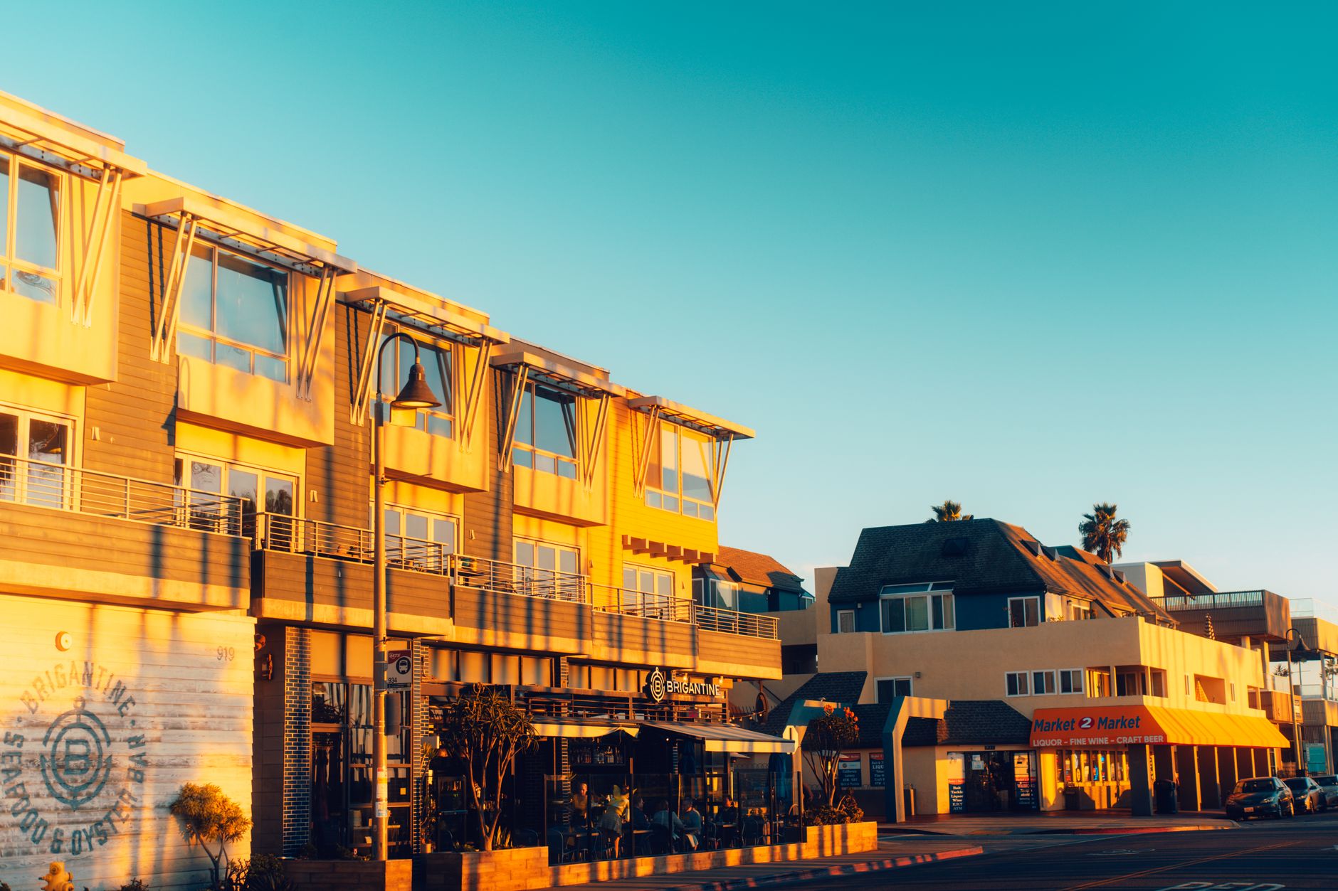 Coastal street view with modern architecture during sunset, creating a warm and inviting atmosphere.