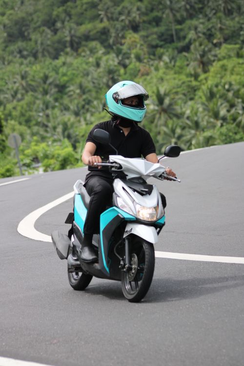 Free A motorcyclist wearing blue helmet riding on a scenic, curvy mountain road. Stock Photo