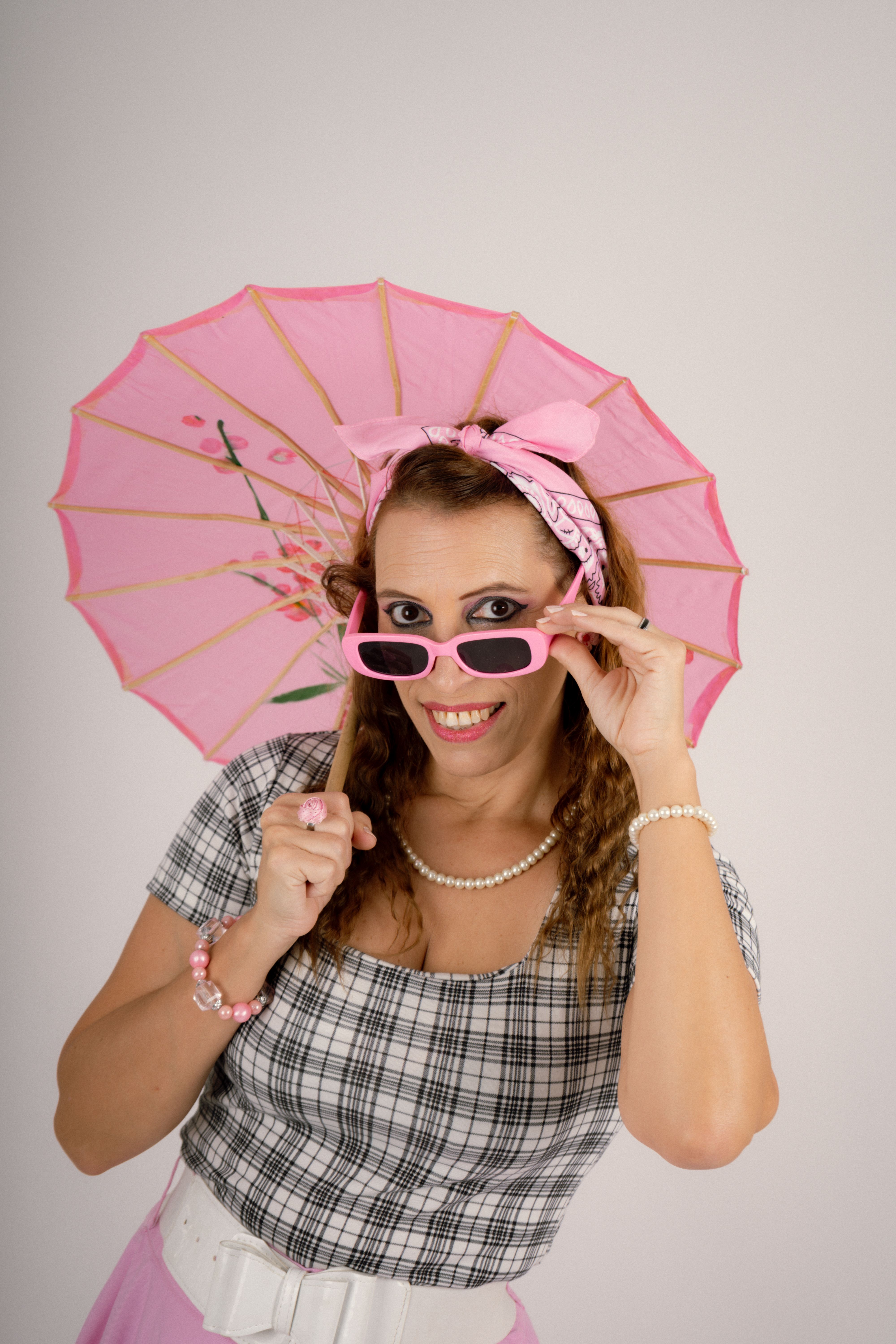 Chic vintage style portrait of a woman with pink sunglasses and parasol, smiling.