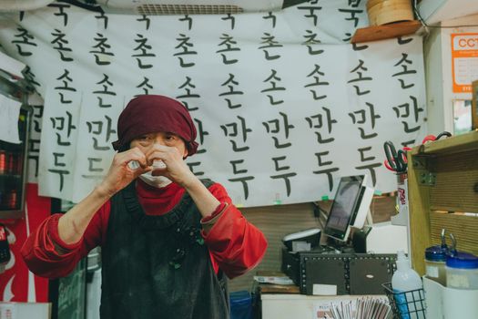 A Seoul street food vendor prepares traditional mandu dumplings in a bustling market.