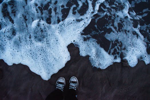 Footsteps in sneakers by foamy ocean waves on Mar del Plata beach in Argentina.