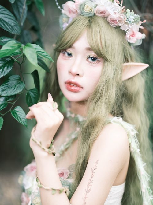 Free Fantasy-themed portrait of a woman with elven ears and floral crown in a forest setting. Stock Photo